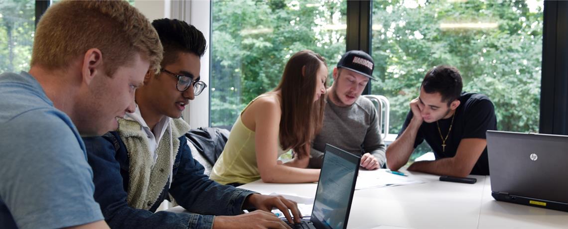 Studierende sitzen an Laptops